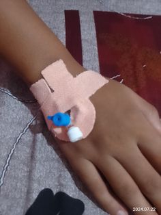 a child's hand with a bandage on it and a blue button in the middle