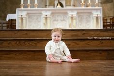 a baby sitting on the floor in front of a church pew