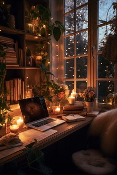 a laptop computer sitting on top of a desk in front of a window filled with candles