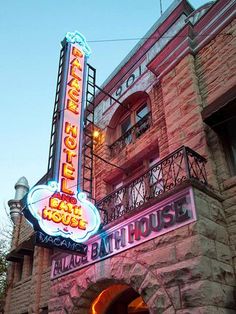 an old brick building with a neon sign on it's side and the entrance