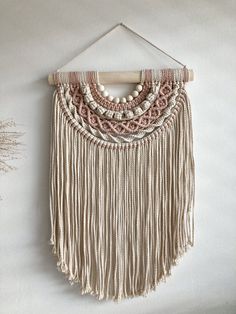 a white wall hanging with beads and tassels