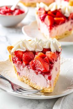 two slices of strawberry cheesecake with whipped cream and fresh strawberries on the top