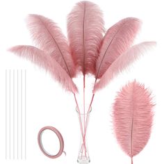 some pink feathers are in a glass vase next to a pair of scissors and tape