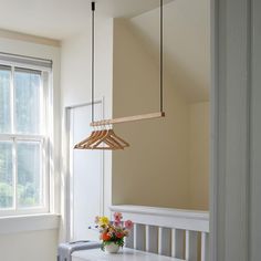 a wooden light fixture hanging from the ceiling over a white bench with flowers on it