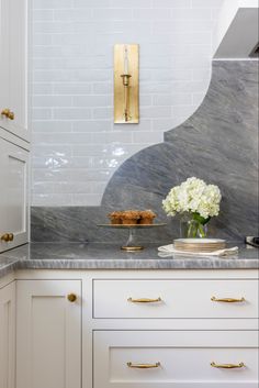 a white kitchen with marble counter tops and gold handles