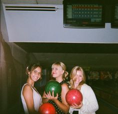 three women holding bowling balls in their hands