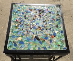 a table that has been made out of glass and pebbles on it, sitting in the street