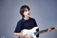 a young man holding a white electric guitar