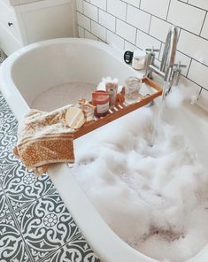 a bathtub filled with foam and soap next to a tiled floor in a bathroom