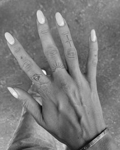 a person's hand with tattoos on it and two fingers in front of them