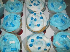 cupcakes with frosting and blue sprinkles are arranged in a box