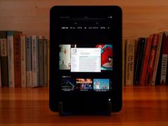 an ipad sitting on top of a wooden table in front of some bookshelves