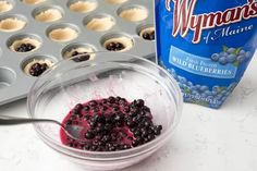 blueberries in a bowl next to muffin tins