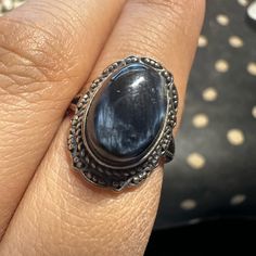 a woman's hand holding a ring with a large blue stone in the middle