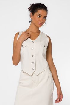 The Kiana Denim Vest is a fun styling piece to add a wardrobe. It has a western vibe with metal buttons and can be worn alone or layered over a top. Material: 100% Cotton. Machine wash Color: Ivory Model is 5'9" and wearing a size S Imported Chic Spring Denim Vest With Button Closure, Trendy Beige Tops With Snap Buttons, Western Style Spring Tops With Buttons, Western White Tops For Spring, Spring Denim Vest With Snap Buttons, Spring Tops With Pockets For Rodeo, Spring Rodeo Tops With Pockets, Trendy White Denim Vest With Pockets, Trendy Button Closure Denim Vest For Day Out