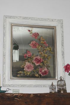 flowers are displayed in front of a mirror on a mantle