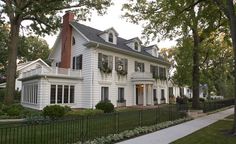 a large white house sitting next to a lush green park