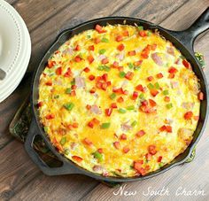 a breakfast casserole in a cast iron skillet next to a cup of coffee