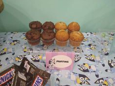 a table topped with muffins next to a box of chocolate chips and an envelope