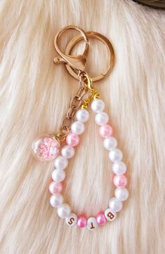 a pink and white beaded keychain on top of a furry surface