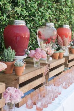 there are many vases and glasses on the table with pink flowers in each one