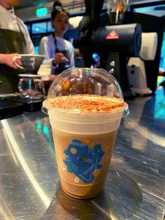 a plastic cup filled with food sitting on top of a counter next to a person