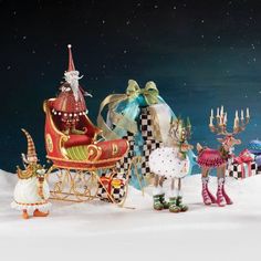 a group of christmas figurines sitting on top of a snow covered ground next to a sleigh