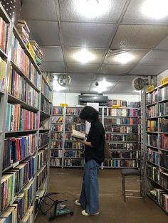 a person standing in front of a bookshelf filled with lots of different kinds of books