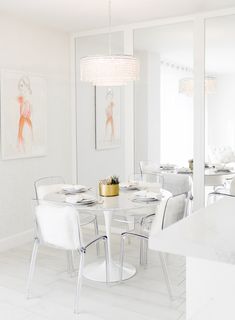 a dining room table with white chairs and plates on it