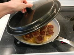 someone is cooking meatballs in a pan on the stove