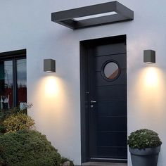 a black front door with two lights on each side and a potted plant next to it