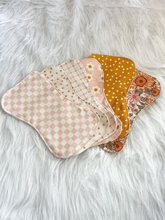 three baby bibs laying on top of a white furnishing covered floor next to each other