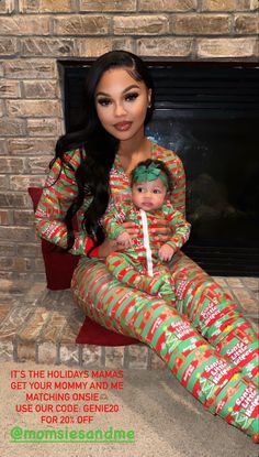 a woman sitting in front of a fire place holding a baby wearing pajamas with candy canes on them