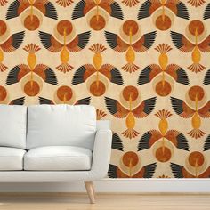 a white couch sitting in front of a wall with an orange and black pattern on it