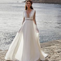 a woman in a wedding dress standing on the beach