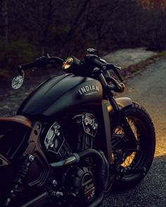 the motorcycle is parked on the side of the road in the evening light, with its lights on