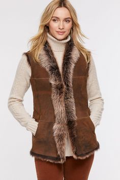 Add warmth and style to any outfit with this uniquely colored Toscana sheepskin vest. The color of an early morning winter sky or a shadow-dappled winterscape, this raw-edge style flatters with a softly draped, collarless open-front design and subtly shaped seams. Two lined slip pockets and an inner zip pocket add wear-everywhere functionality. Pair with a midi skirt and boots for a romantic look, or over city attire for upscale style—either way, you'll be gorgeous and cozy warm. Fall Sheepskin Sleeveless Vest, Sleeveless Sheepskin Vest For Fall, Elegant Brown Winter Vest, Brown Faux Fur Trim Vest For Fall, Brown Vest With Faux Fur Trim For Fall, Midi Skirt And Boots, Sheepskin Vest, Morning Winter, Skirt And Boots