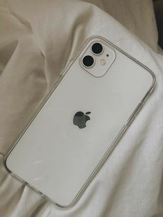 an iphone case sitting on top of a bed next to a white sheet with two black buttons