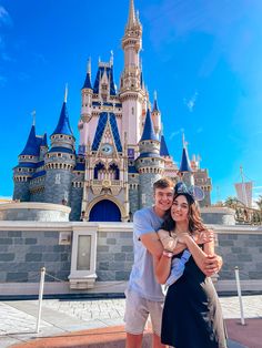 a man and woman pose in front of the castle at disney world with their arms around each other