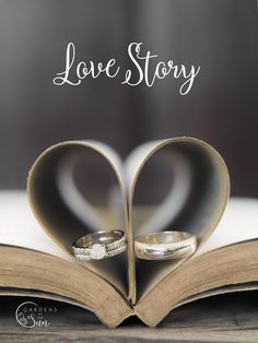 two wedding rings sitting on top of an open book with the words love story written over it