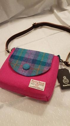 Beautiful genuine Harris Tweed Handbag. Can be used as a shoulder or cross body bag. The body of the bag is a bright pink and the covering flap is in a modern teal, purple and blue tartan with a contrasting harris tweed covered teal button which matches the strap tags. The bag is finished with a black or dark brown natural cork strap. The interior of the bag is a lovely Liberty Print to compliment the bag. The pattern of the lining fabric may vary from the pictures. A lovely Harris Tweed gift. T Purple Tartan, Tweed Handbag, Travel Laundry Bag, Repurposed Fabric, Tweed Bag, Dinosaur Fabric, Cross Shoulder Bags, Upcycled Bag, How To Make Purses