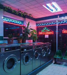 a laundry room filled with washers and dryers next to a neon lit sign