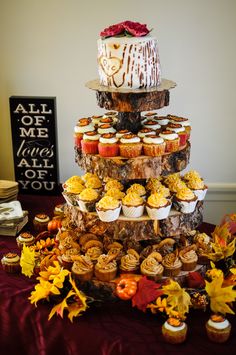 a three tiered cake with cupcakes and candy on the top is surrounded by autumn leaves