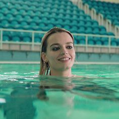 a woman is swimming in the pool with her head above water and looking at the camera