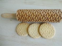 three cookies sitting next to a rolling pin