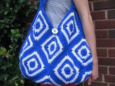 a woman holding a crocheted blue and white purse