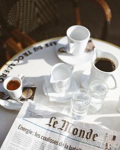 two cups of coffee sit on top of a newspaper