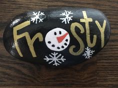 a painted rock with the word frosty on it and a snowman's face