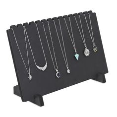 six necklaces are displayed on a black stand