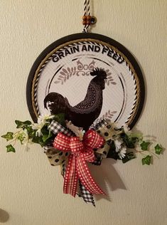 a rooster is hanging on the wall next to some flowers and ribbon with words that read grain and feed